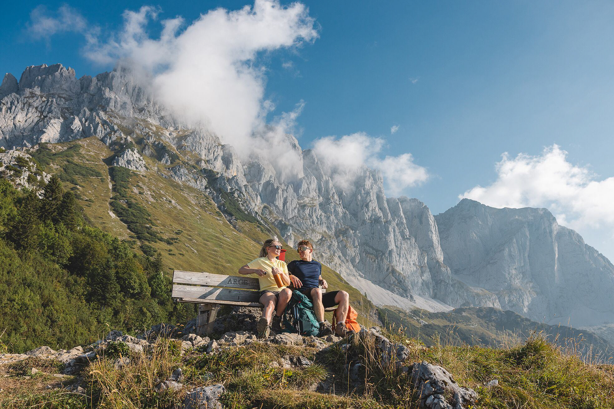 Dan and Abby Greenway on a bench beneath the Wilder Kaiser mountains in the Austrian Alps